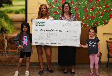 Two students and principal pose with big commemorative check for $500.