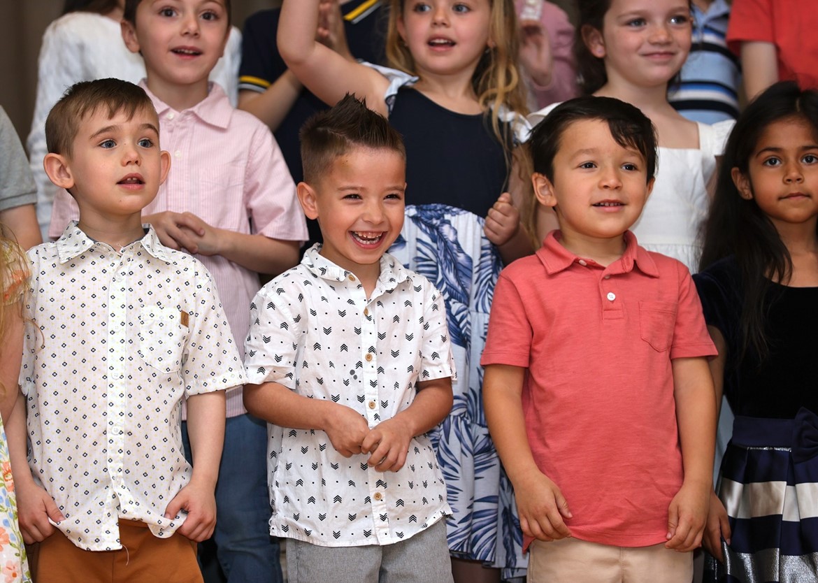 Indian Hills kindergartener smiles on stage during Spring Showcase.