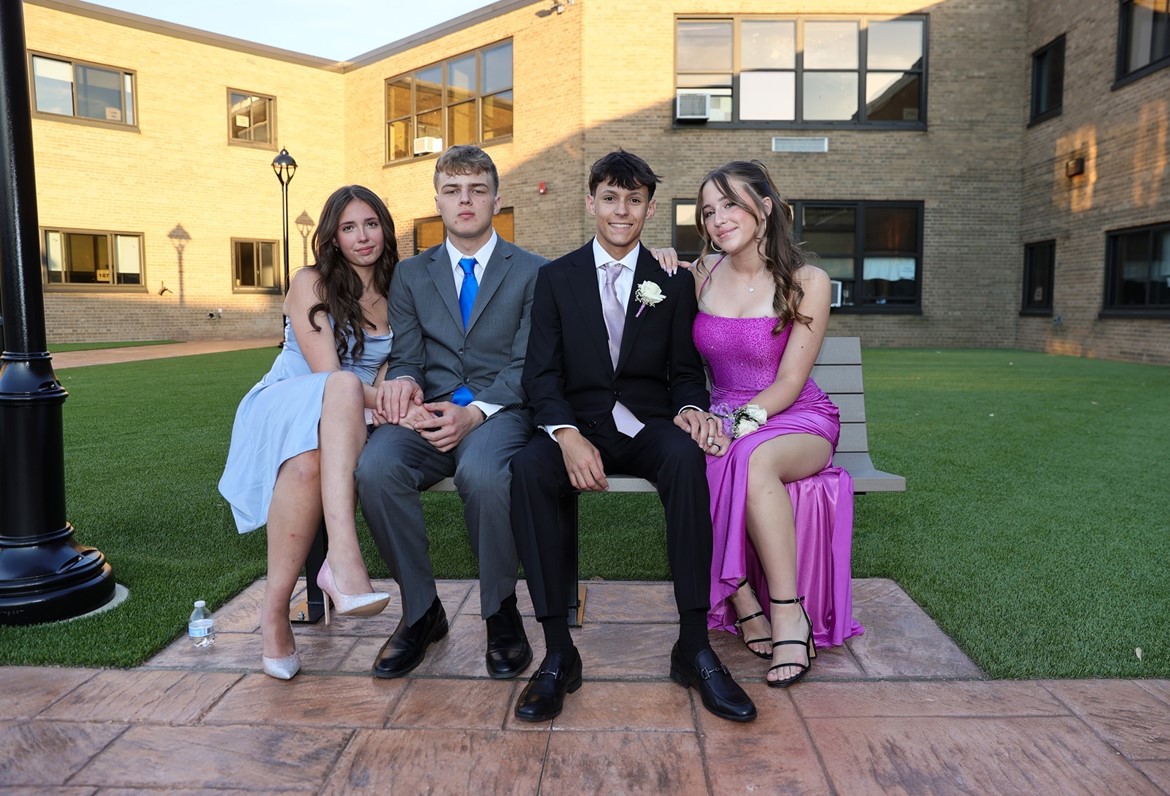 Two junior couples pose on bench in CHS courtyard during Junior Banquet.