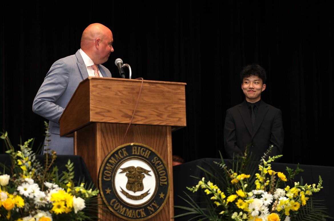 Student on stage as presenters speaks about his accomplishments during Senior Awards at CHS.