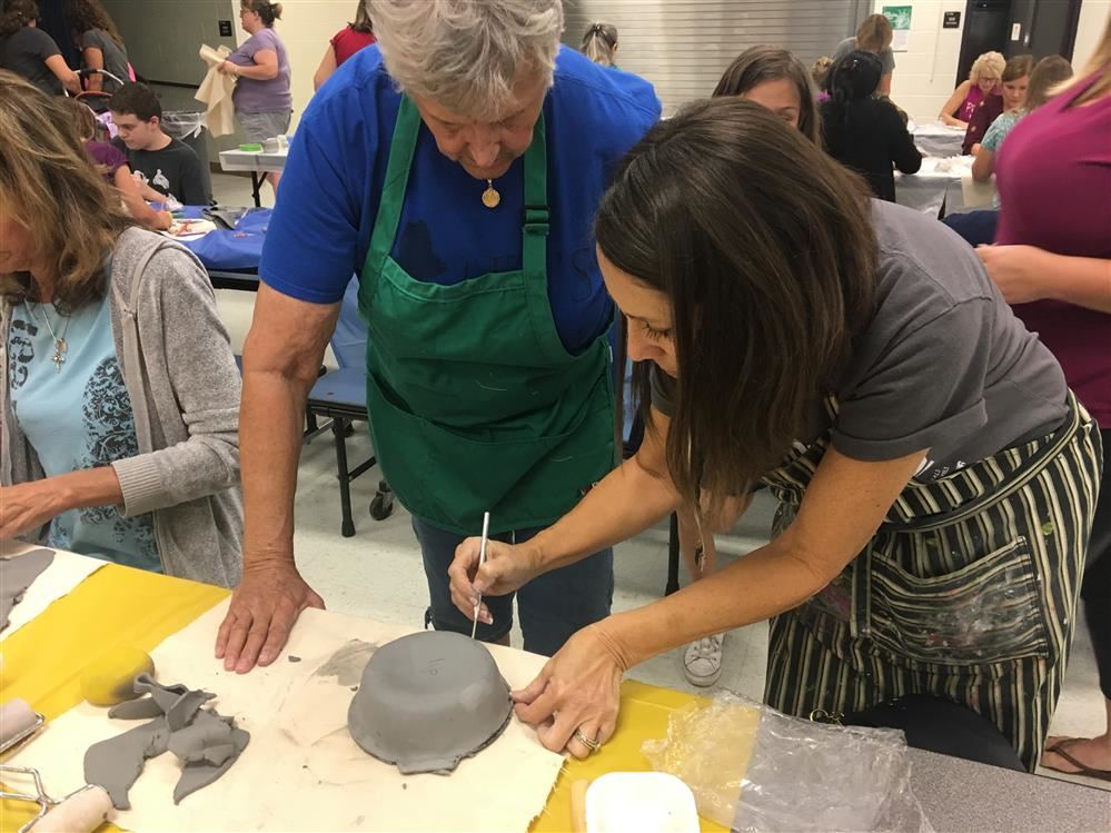 art teacher helping adult make a bowl