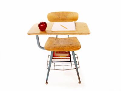 A student's desk with an apple, pencil, and paper on it. 