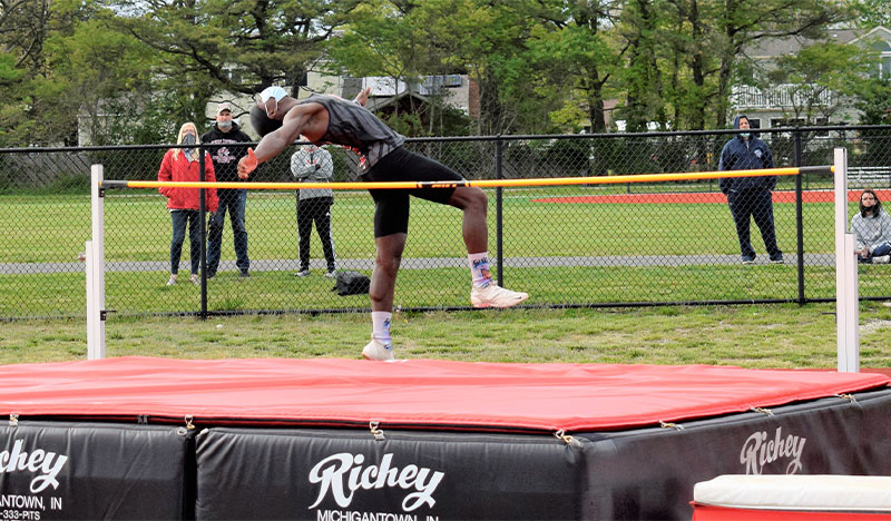 Students high jumping in mid air over bar