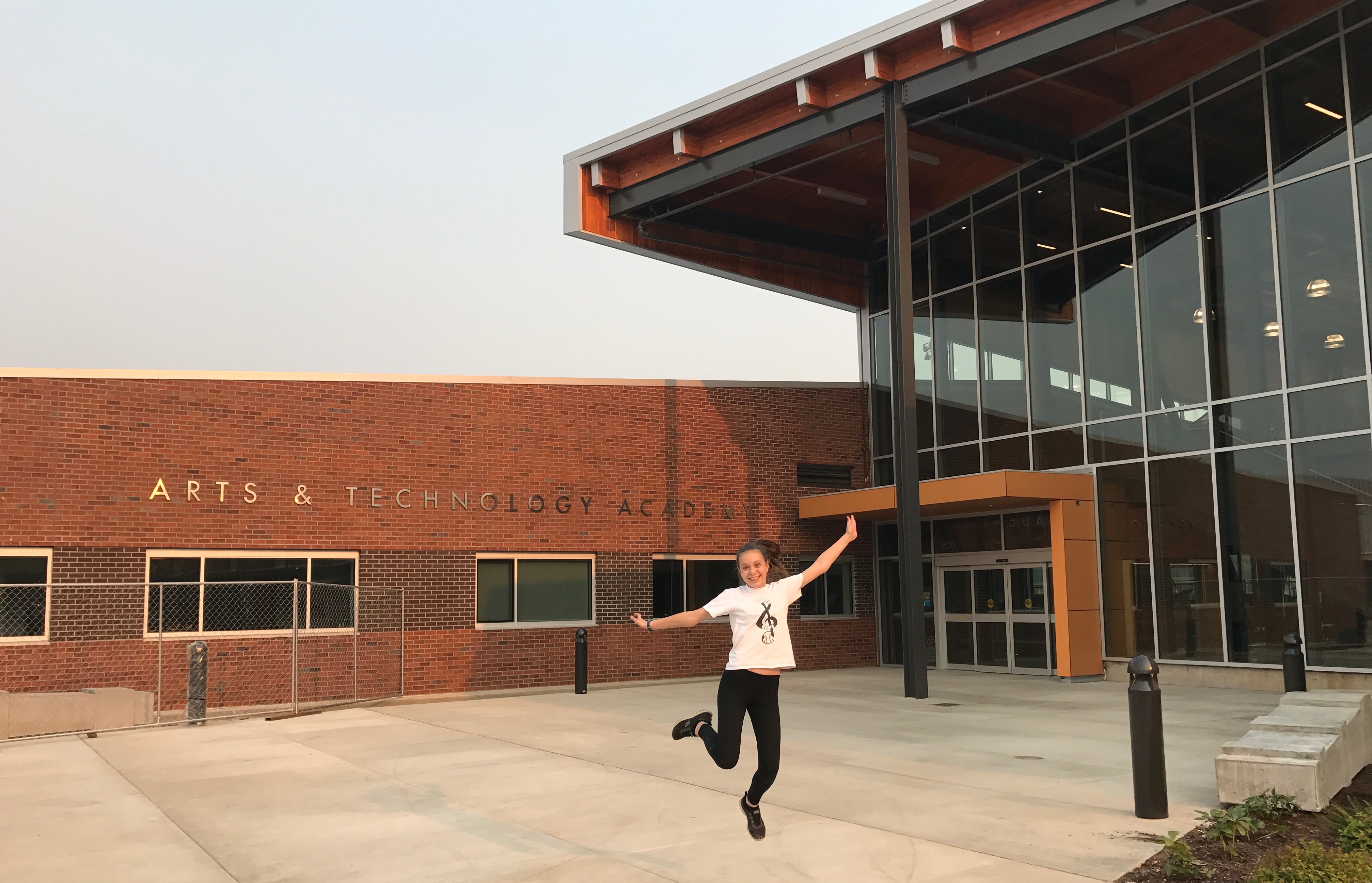 An excited student jumps to celebrate the new Arts & Technology Academy building