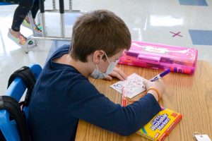 Student working at desk in classroom, following health and safety protocols