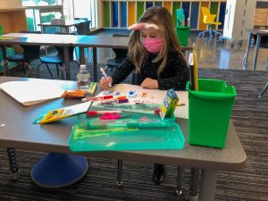 Student working at desk in classroom, following health and safety protocols