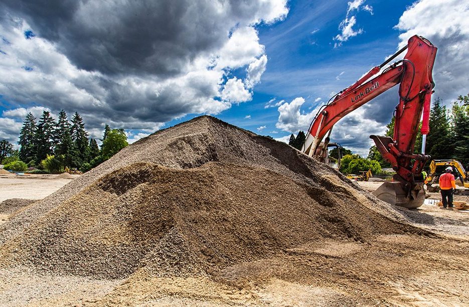 North build: view of a large dirt pile and a maching at rest in the middle of the work site.