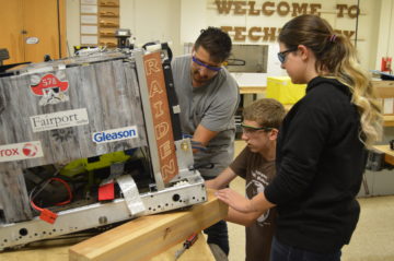 Teacher works with two students on robot