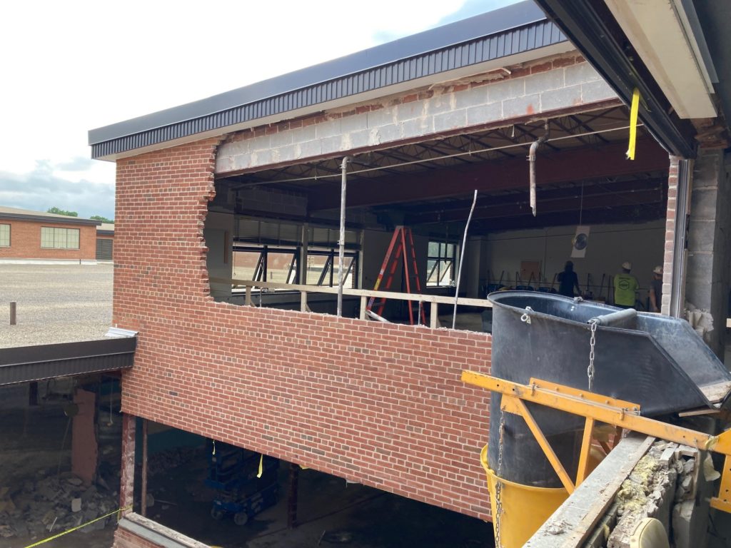 A demolished brick wall overlooking a courtyard