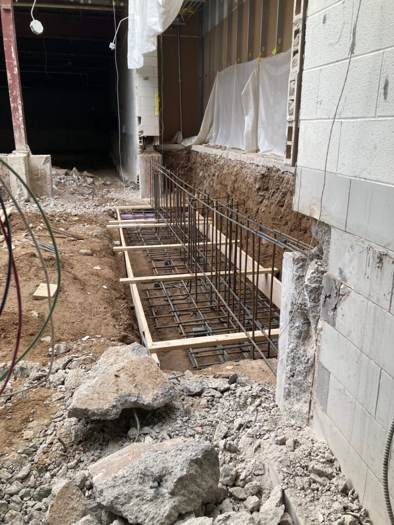 Metal and wood forms built on the floor to receive new poured concrete foundations