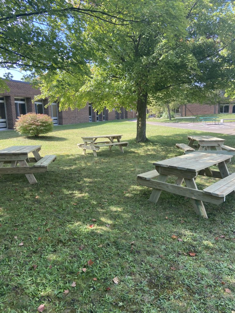 Four picnic tables in a shady courtyard