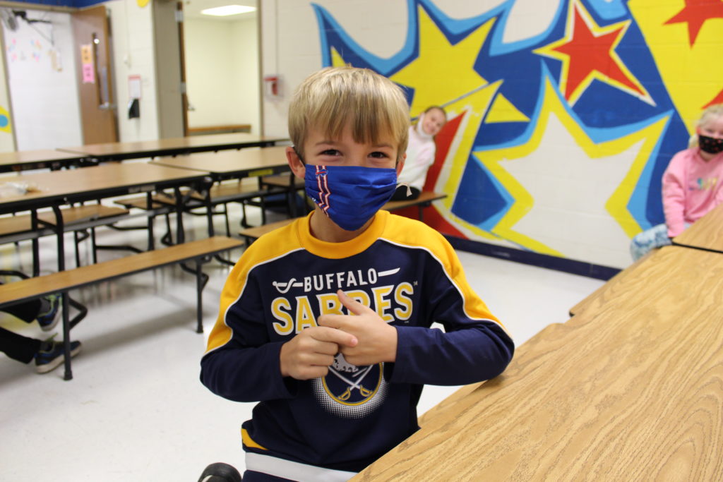 Student looks at camera while sitting at a school lunch table