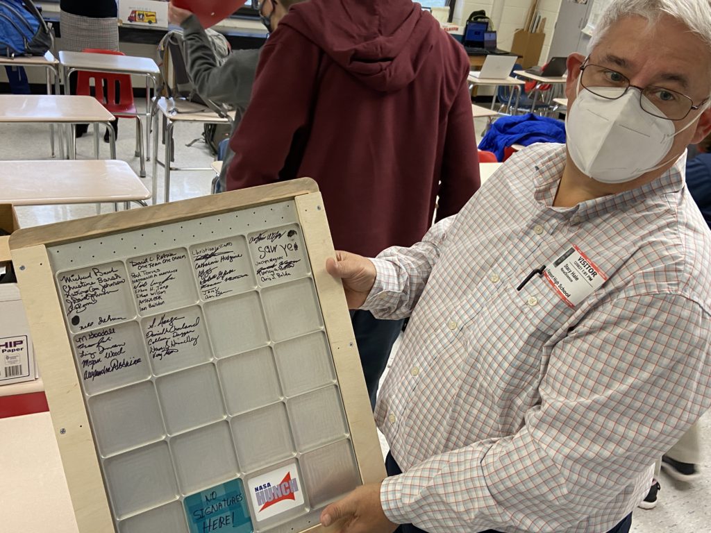 NASA representative Stacy Hale holds up a metal locker plate signed by HUNCH advisors