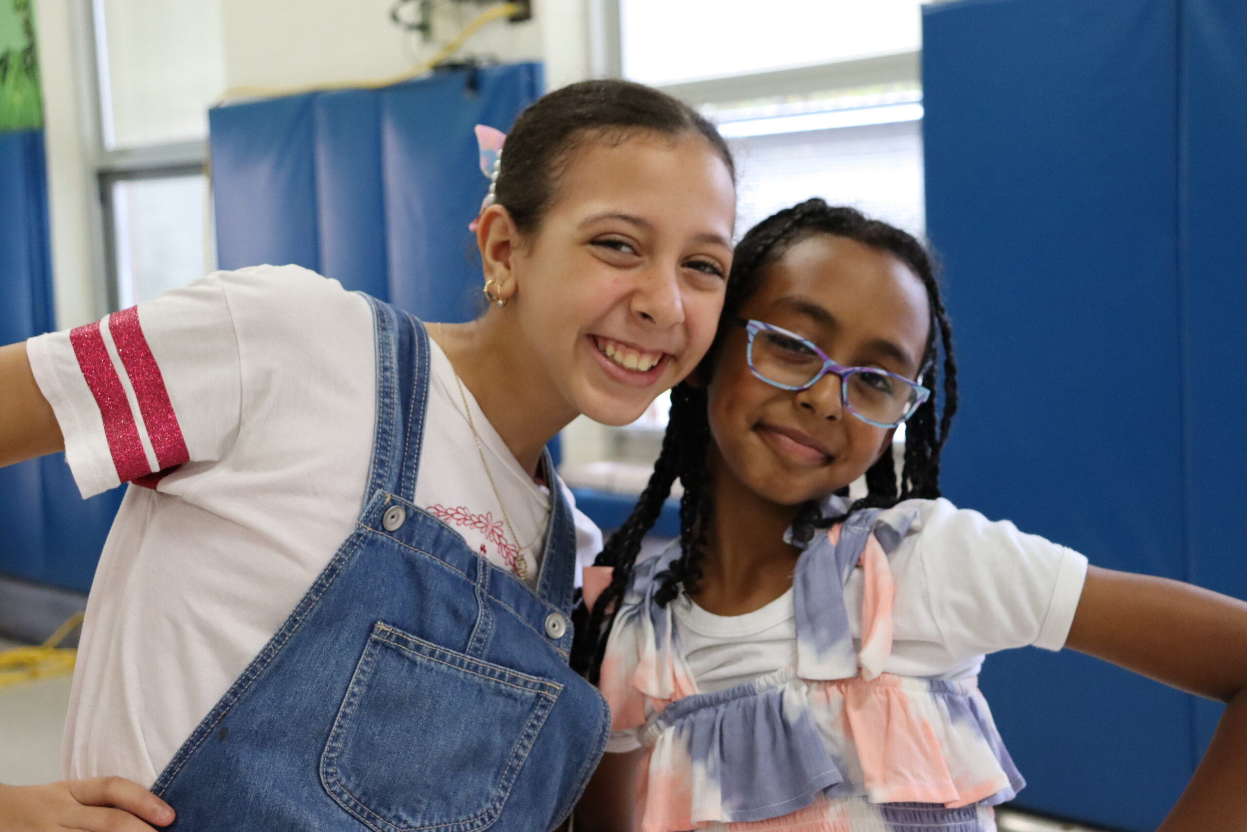 Two elementary students smile at the camera in a school lunchroom