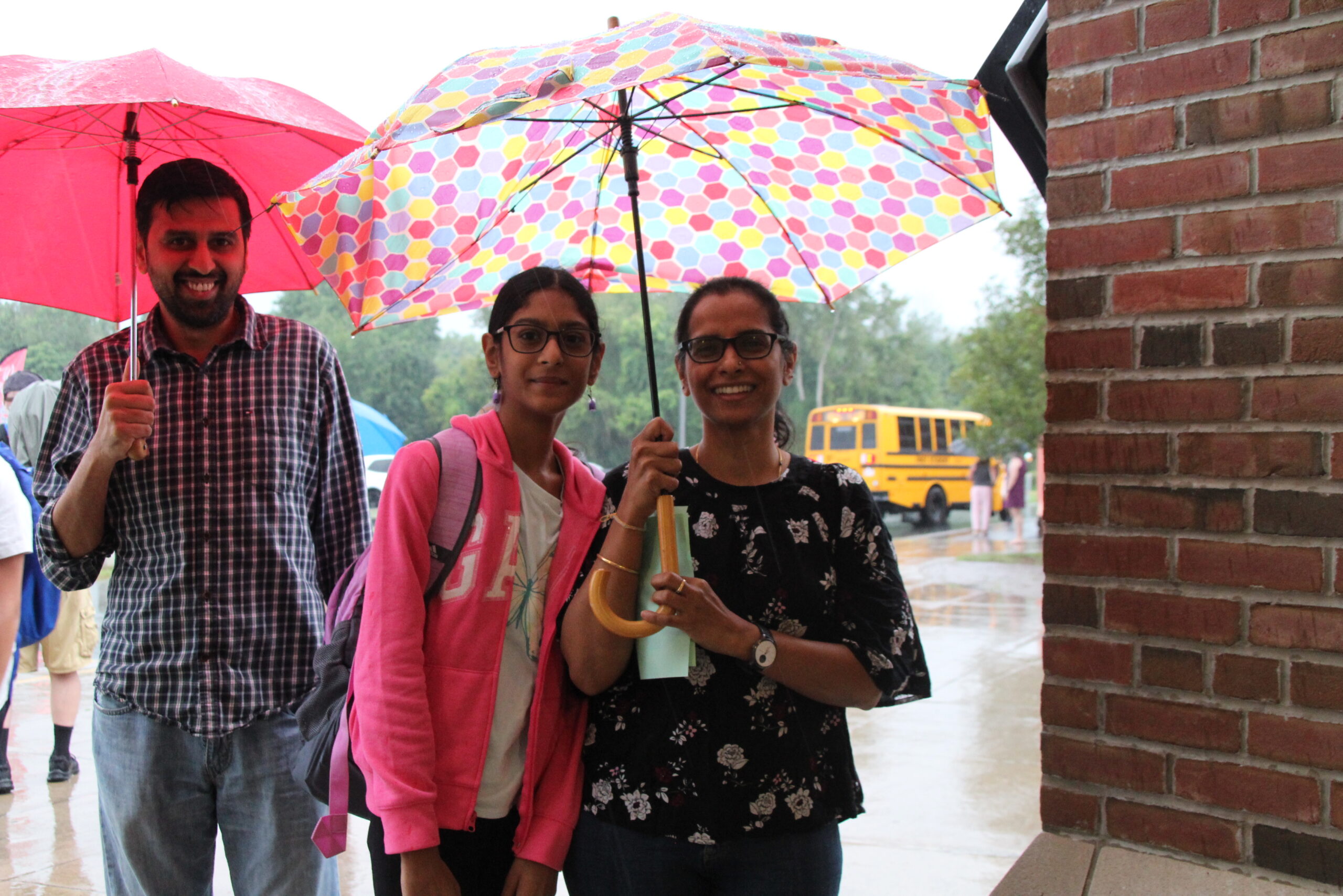 Two adults walk a middle school student to the front door of a a school