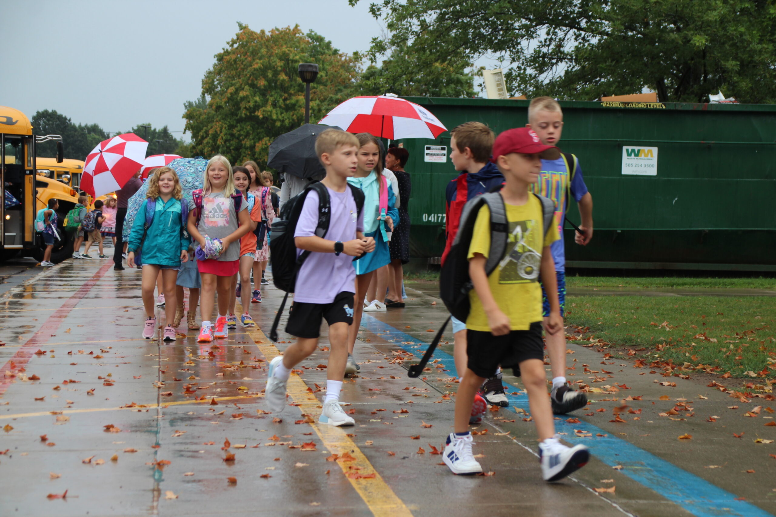 Elementary students approach school from school buses