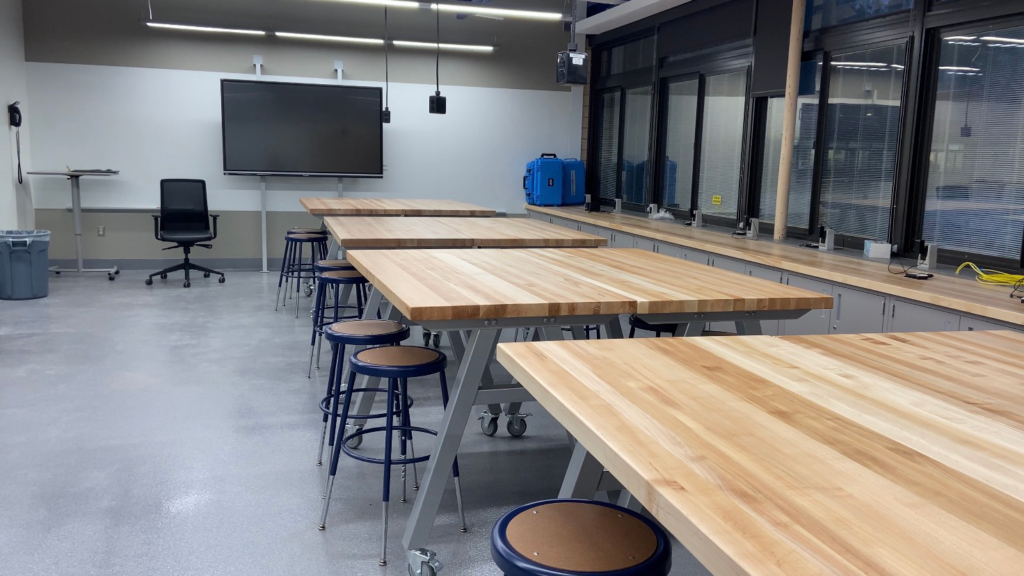 Rows of high, wood-topped worktables with stools