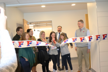 Two students cut a large ribbon.