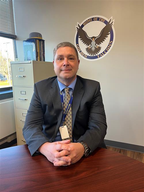 Mr. Jordan sitting at a table with the FCS Logo behind him