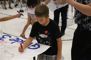 Student writing his name on PBIS wall. 