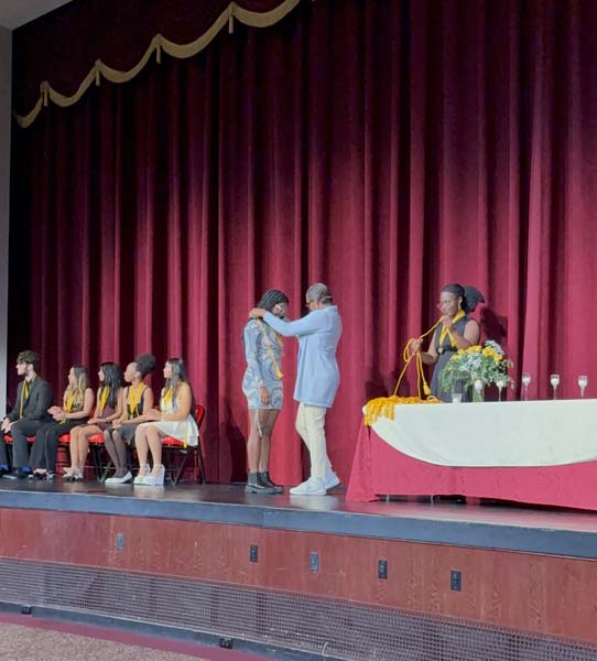 Students on stage receiving awards. Students on stage receiving awards.
