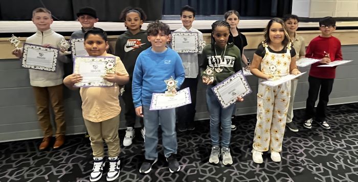 Fremont City Schools 4th grade students in the Fremont Ross High School Performing Arts Center in front of the stage posing with awards.  