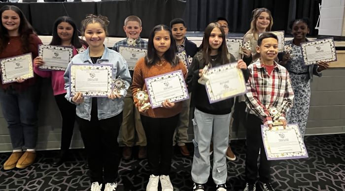 Fremont City Schools 5th grade students in the Fremont Ross High School Performing Arts Center in front of the stage posing with awards.  