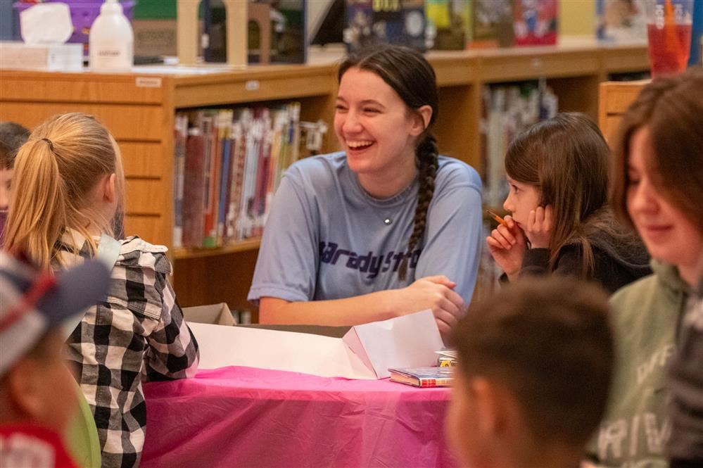  A High School students smiles while working with elementary kids