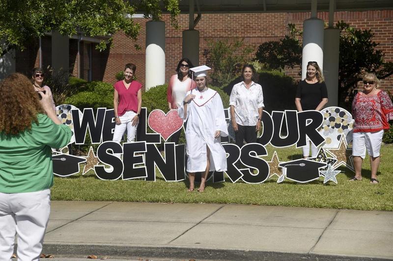 A Glynn Academy graduate takes a photo in front of Oglethorpe Point Elementary.