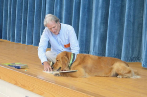 Ronald Binkney and his dog Lucky, a golden retriever and \"silent reader,\' share a book with students at FACES preschool.