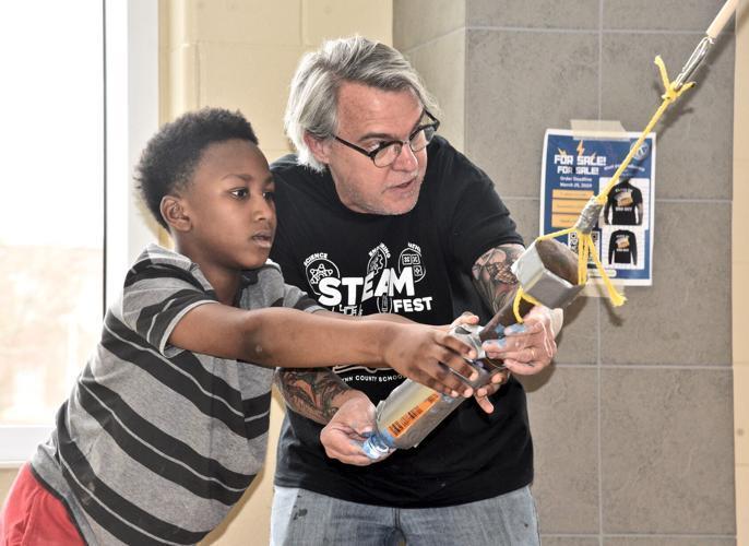 Jane Macon Middle School science teacher Abner Zachary shows a student how a pendulum works at GCSS\' recent STEAMFest and Literacy Fair at Brunswick High.