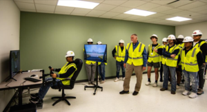 With instructor Jeff Holland and his GICCA classmates watching, Edgar Bautista operates the controls of a forklift on a simulator.