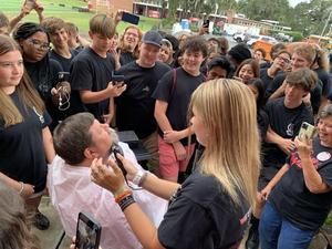 Students helped Glynn Academy band director Chris Duke shave his beard last week to fulfill a promise Duke made. If the students sold 2,500 discount cards, he committed to shaving his beard. If they sell 3,000, he\'ll shave his head.