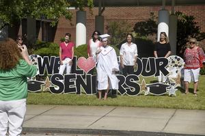 A Glynn Academy graduate takes a photo in front of Oglethorpe Point Elementary.