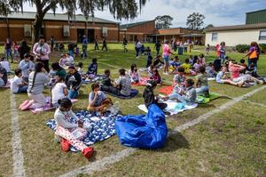 The playground was marked off in a grid for parents and children to have a picnic and read a new book at Goodyear Elementary\'s Lunch and Learn.