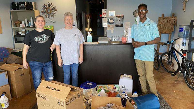 Donna Howard, left, and Maria Gamble, founders of Saved By Grace, receive donations collected through the \"Socktober & More\" initiative led by Brunswick High sophomore Chanthony Andrews Jr., right.