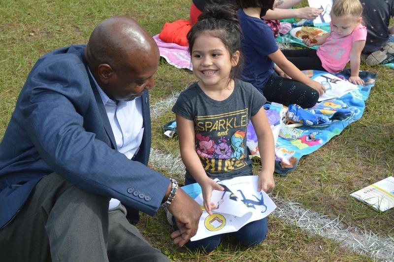 Mayor Cornell Harvey reads Friday with a student at Goodyear Elementary during the school\'s Lunch and Literacy on the Lawn event.