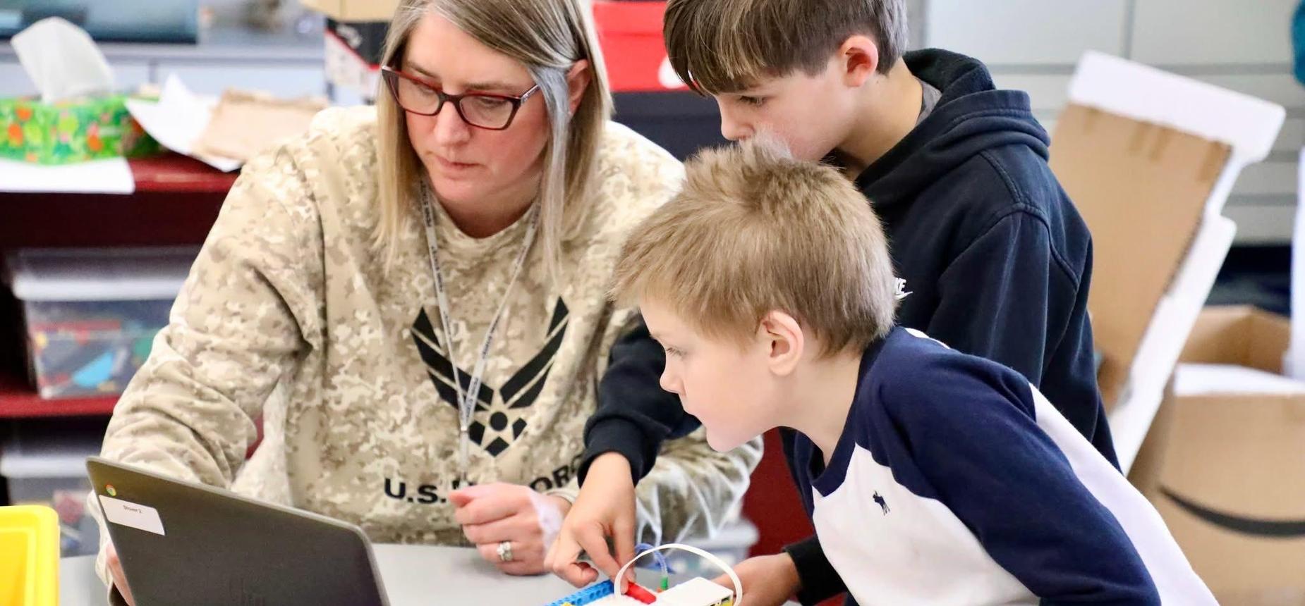teacher and two students looking at computer