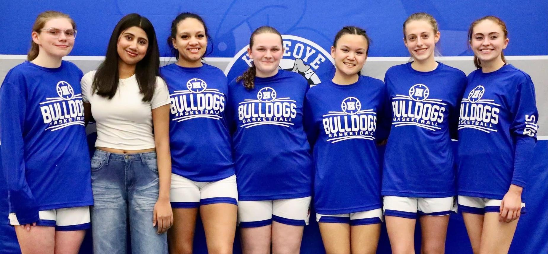 7 girls in basketball uniforms standing in a row