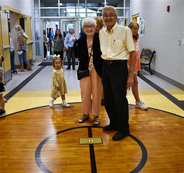 Man and woman stand on wood from former gym floor