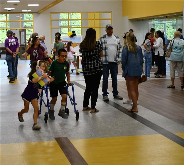 Two kids in front of crowded group in main hall