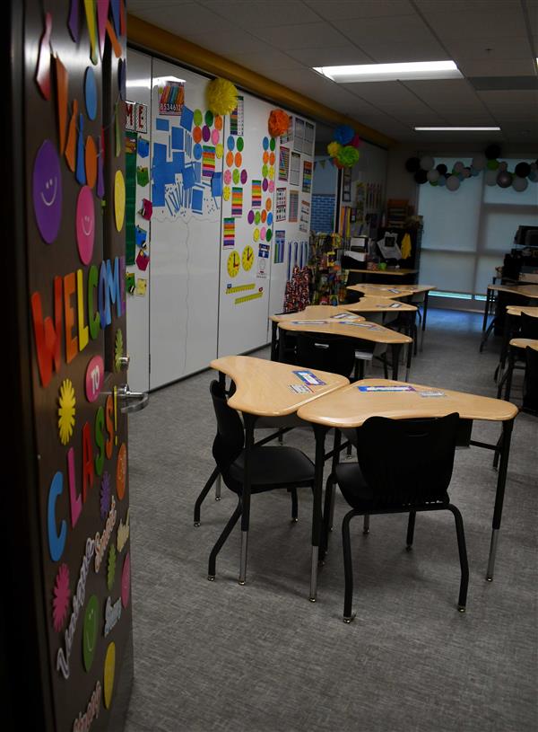 Classroom with colorful door decorations and desks inside arranged as tables