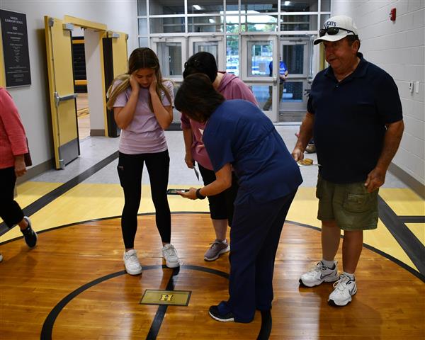 Four people look at basketball floor circle from old gym