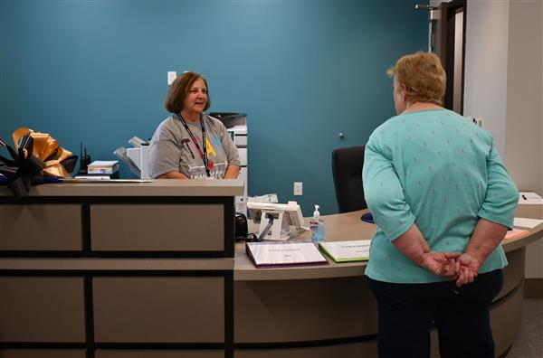 Woman behind desk talks to another woman