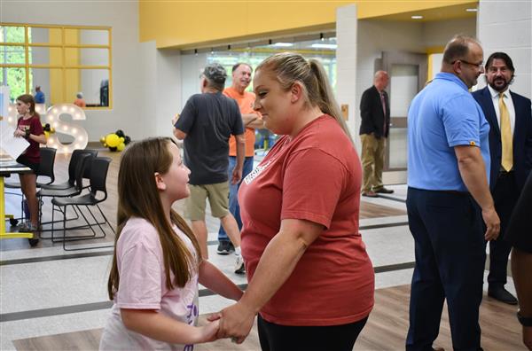 Woman talks to young girl while holding hands with several people nearby