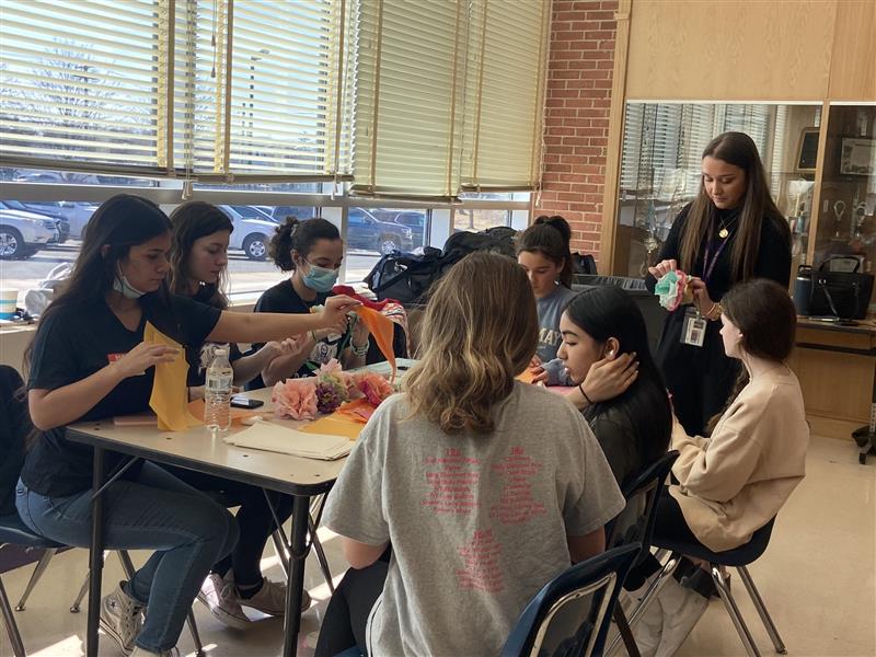 IHS world language honor society students and IMS students sit at a table engaging in language immersion activities