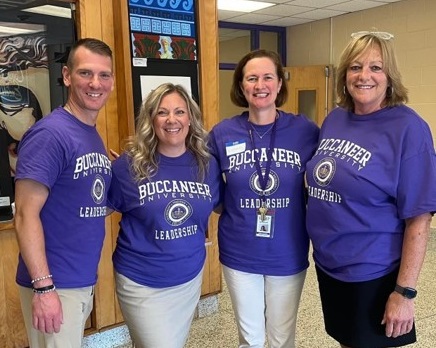 photograph of the Islip High School Leadership team (L to R C. Rizzuto, M. Stern, L. Gonzalez, L.. Ward). All four are wearing purple "Buccaneer University Leadership" T-shirts