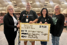 Four individuals standing with a large check