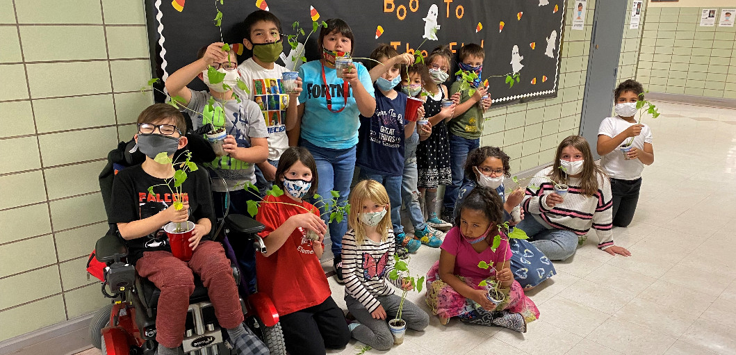 2nd graders showing the kidney beans they grew for their plant life cycle unit