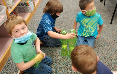 Estudiantes de jardín de infantes trabajando en equipos apilando vasos para construir torres